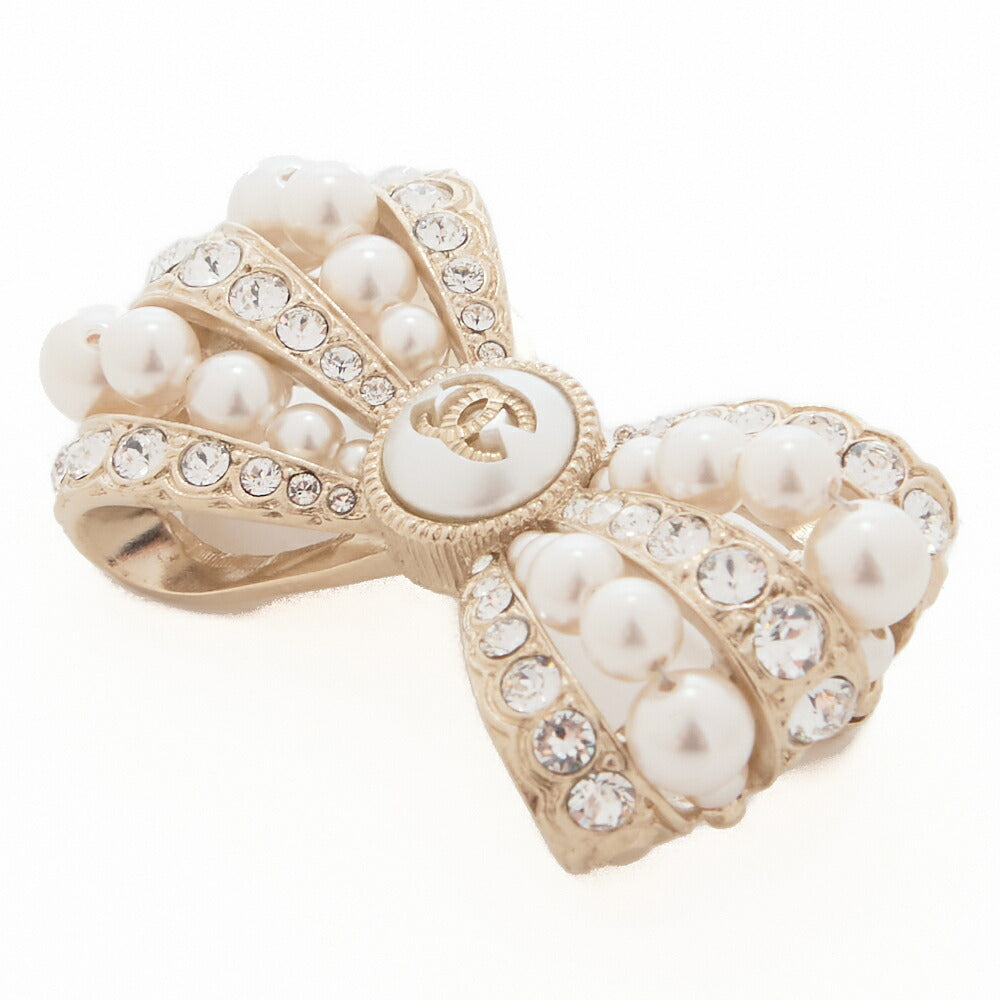 Broche d'occasion en ruban Coco Mark, perle, strass, plaqué or, matériel doré. D'occasion